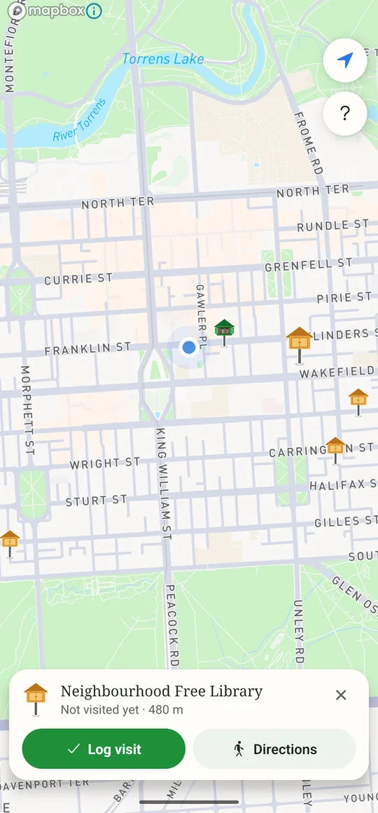 A library selected on the map of central Adelaide, with a card showing its name, how far away it is, and buttons to log a visit or get directions